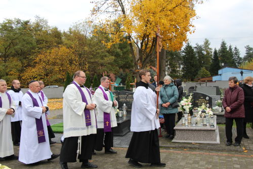 Procesja na cmentarzu w Smardzewicach. Pierwszy idzie Franciszkanin z krzyżem. Za nim idą Księża z założonymi purpurowymi stułami.